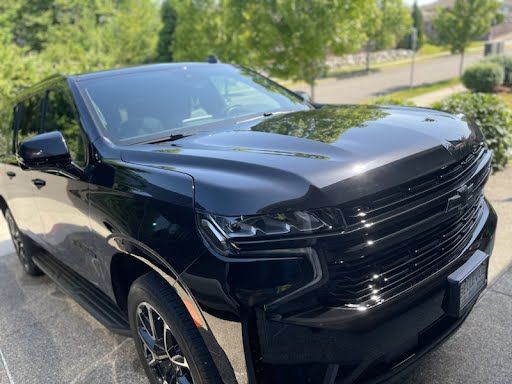A black suv is parked in a driveway in front of a house.