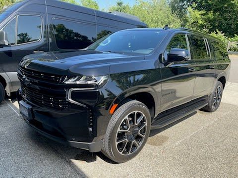 A black suv is parked next to a van in a parking lot.