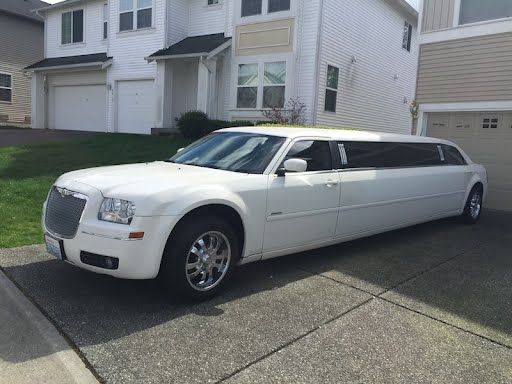 A white limousine is parked in front of a house.