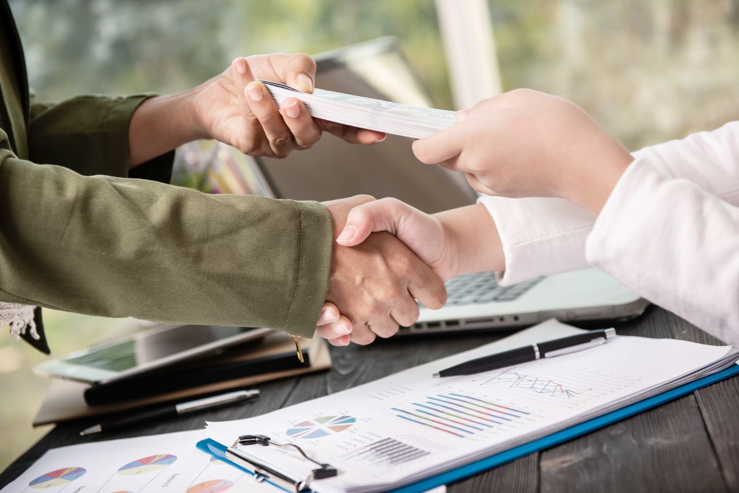 A person is shaking hands with another person while holding a piece of paper.