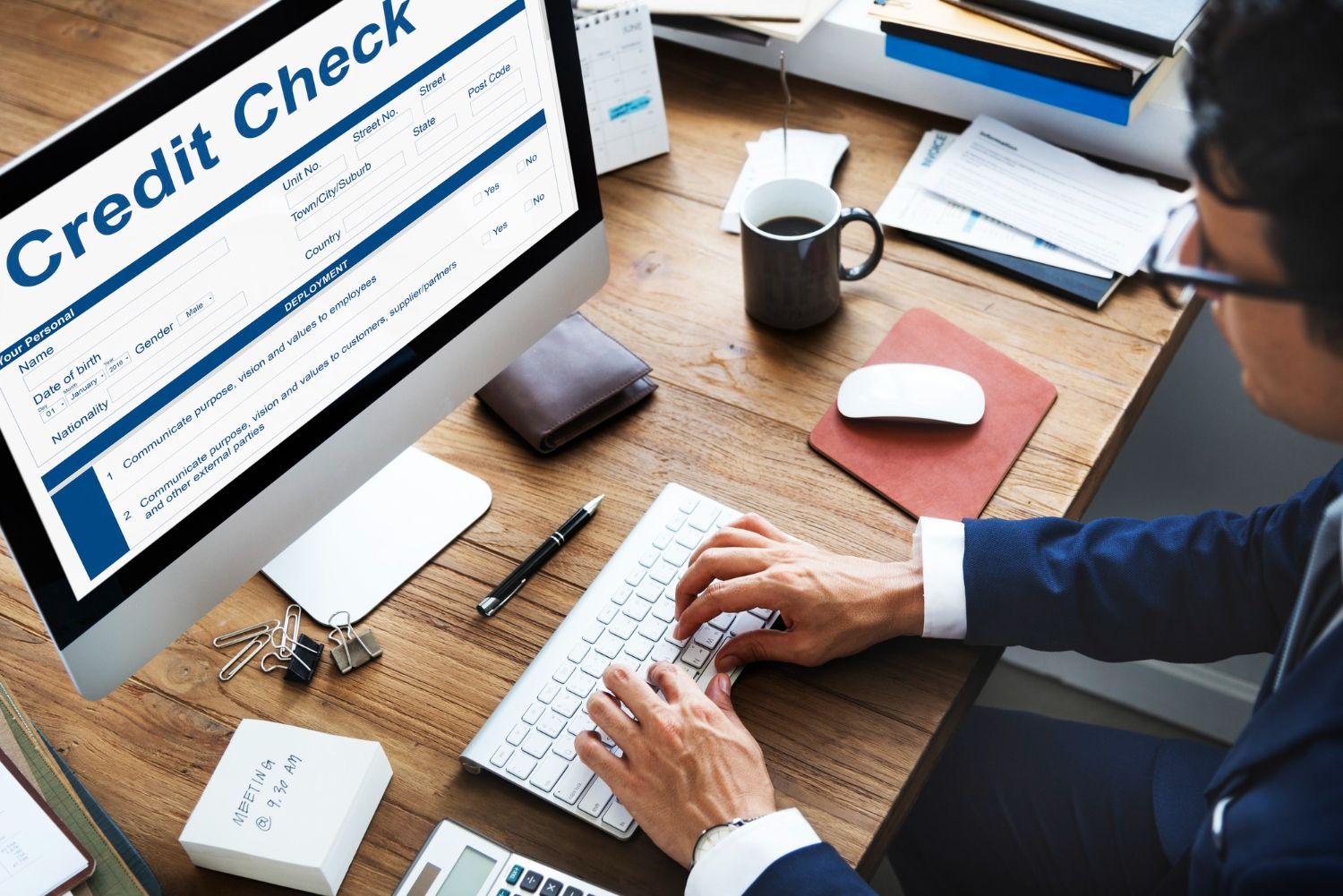 A man is typing on a computer with a credit check on the screen.