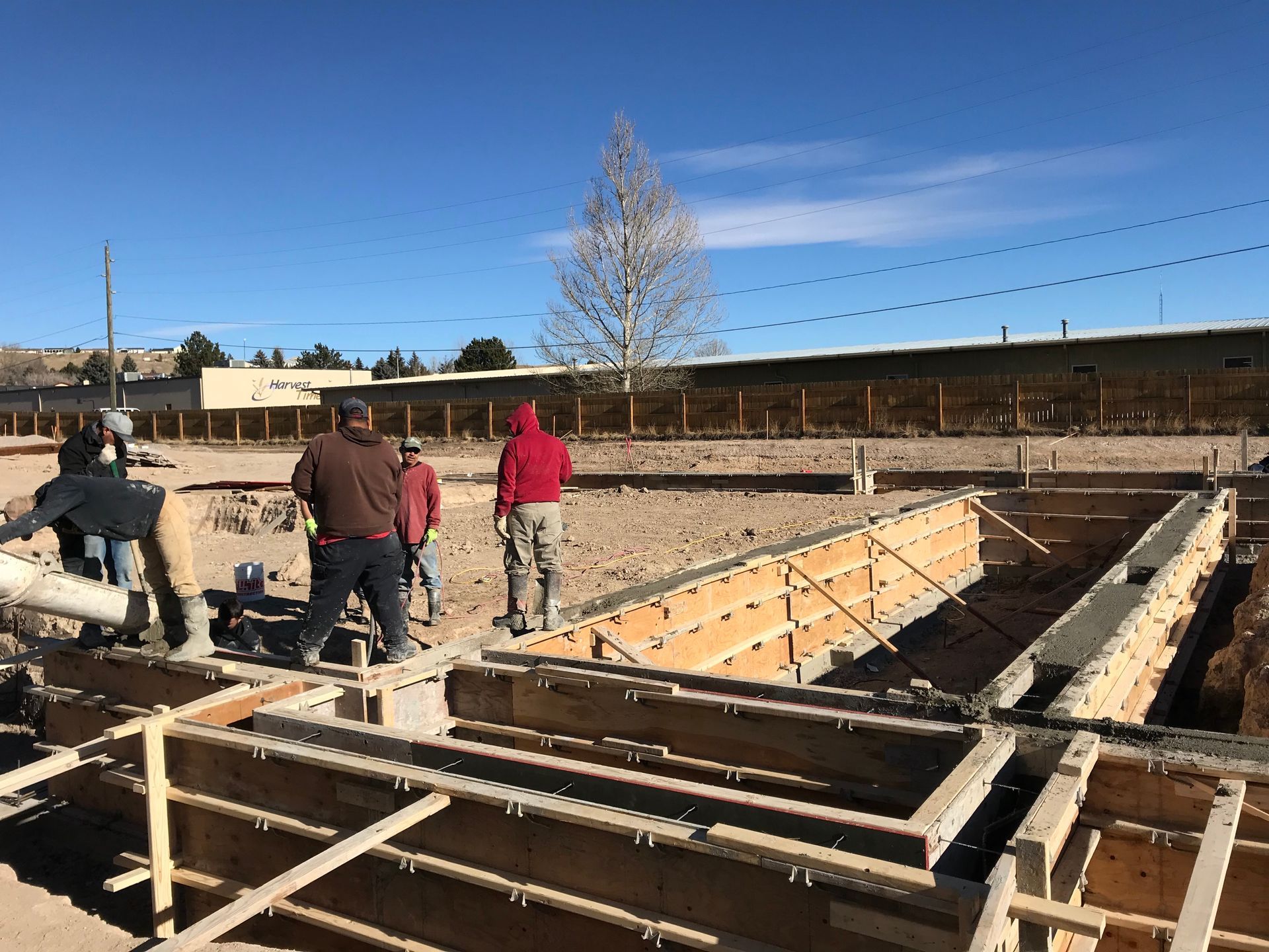 Construction site with unfinished concrete walls, stairs, and a worker laying bricks.