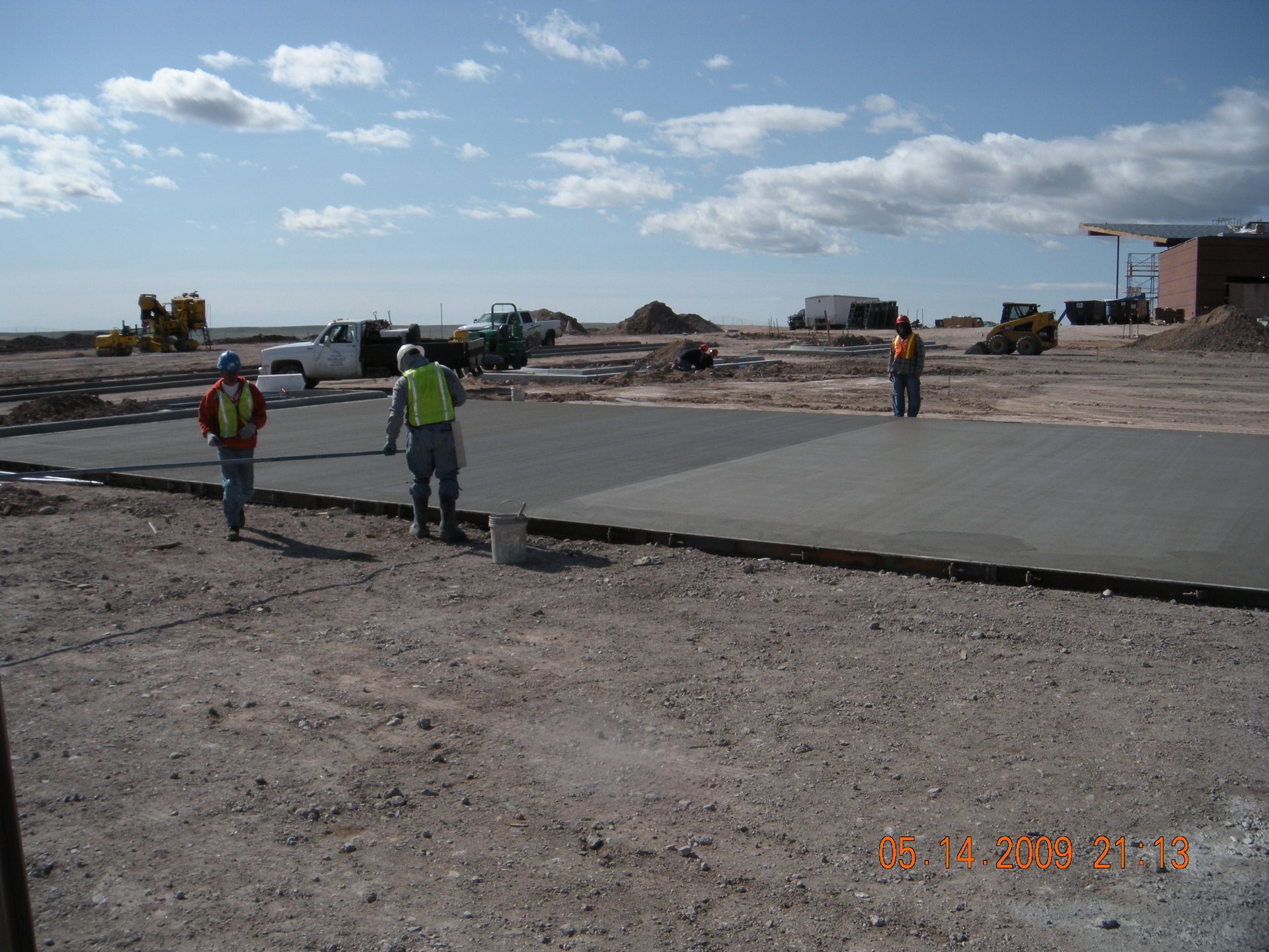 Workers smoothing wet concrete for a sidewalk with a trowel, outdoors.