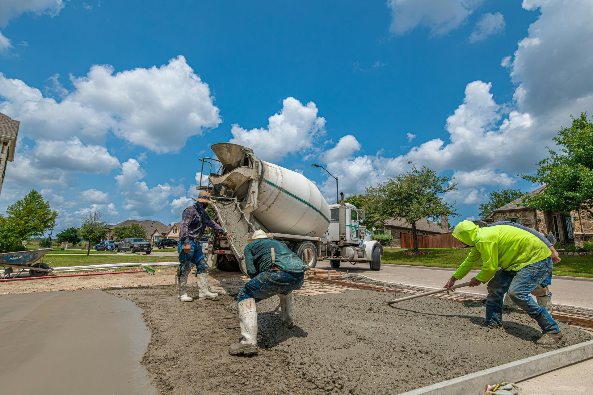 Construction workers pouring concrete on a road under a bright blue sky