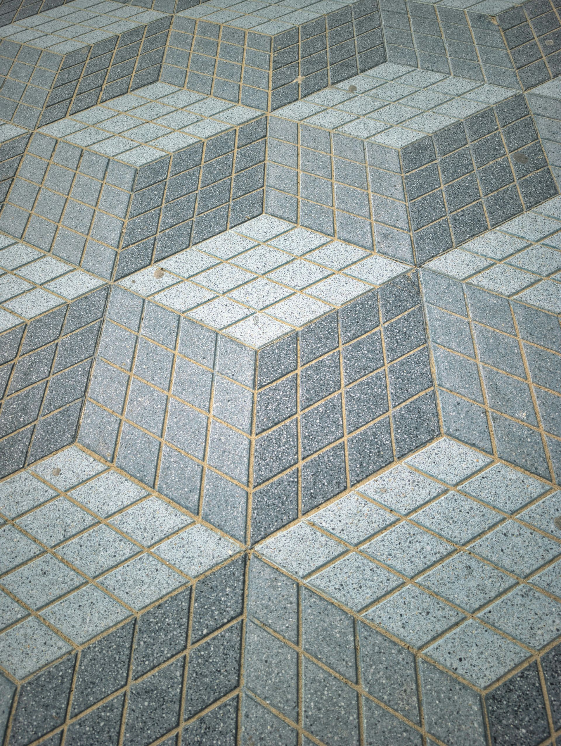 Geometric stone pavement with raised square-topped blocks in gray and beige tones
