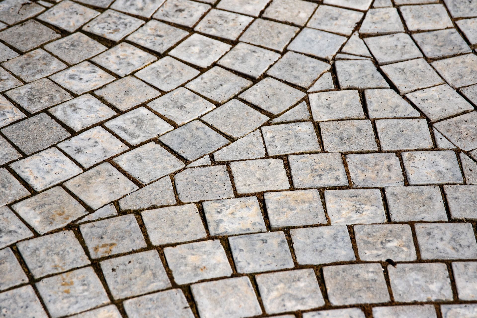 Close-up of irregular gray cobblestone paving with a curved pattern and dark grout lines