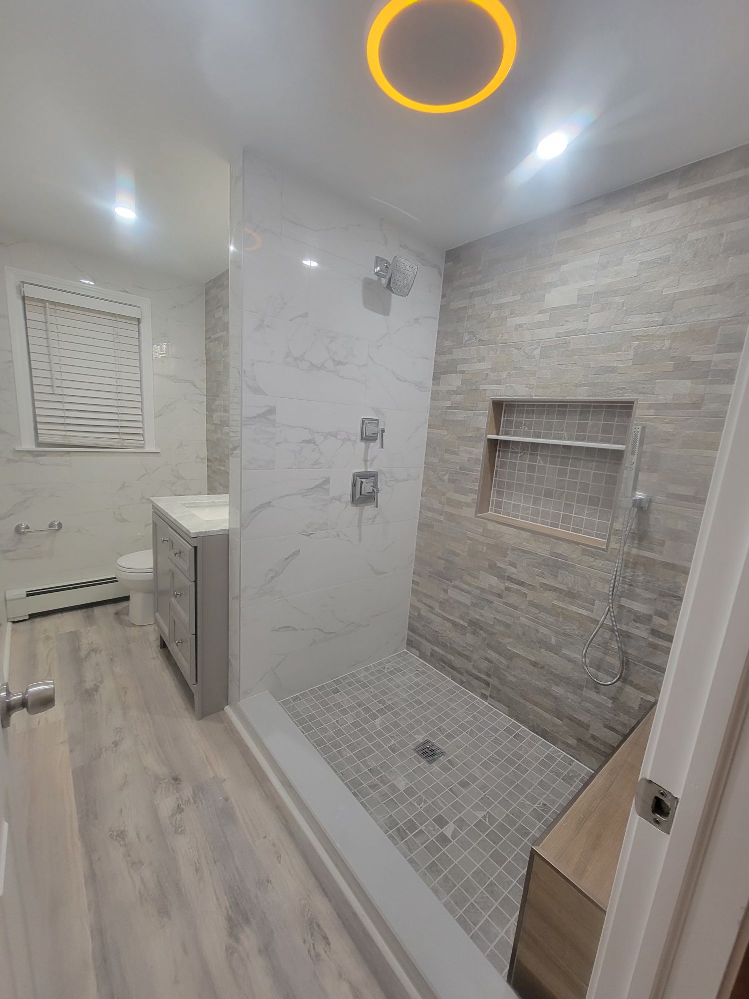 Modern, bright bathroom with a glass shower, soaking tub, and double vanity. Skylight and windows provide natural light.
