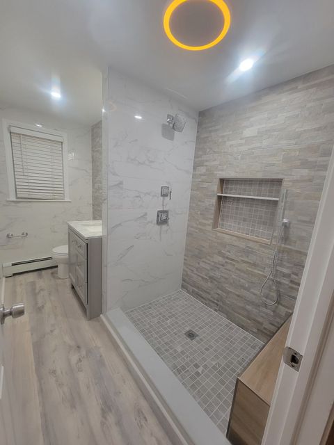 Modern, bright bathroom with a glass shower, soaking tub, and double vanity. Skylight and windows provide natural light.