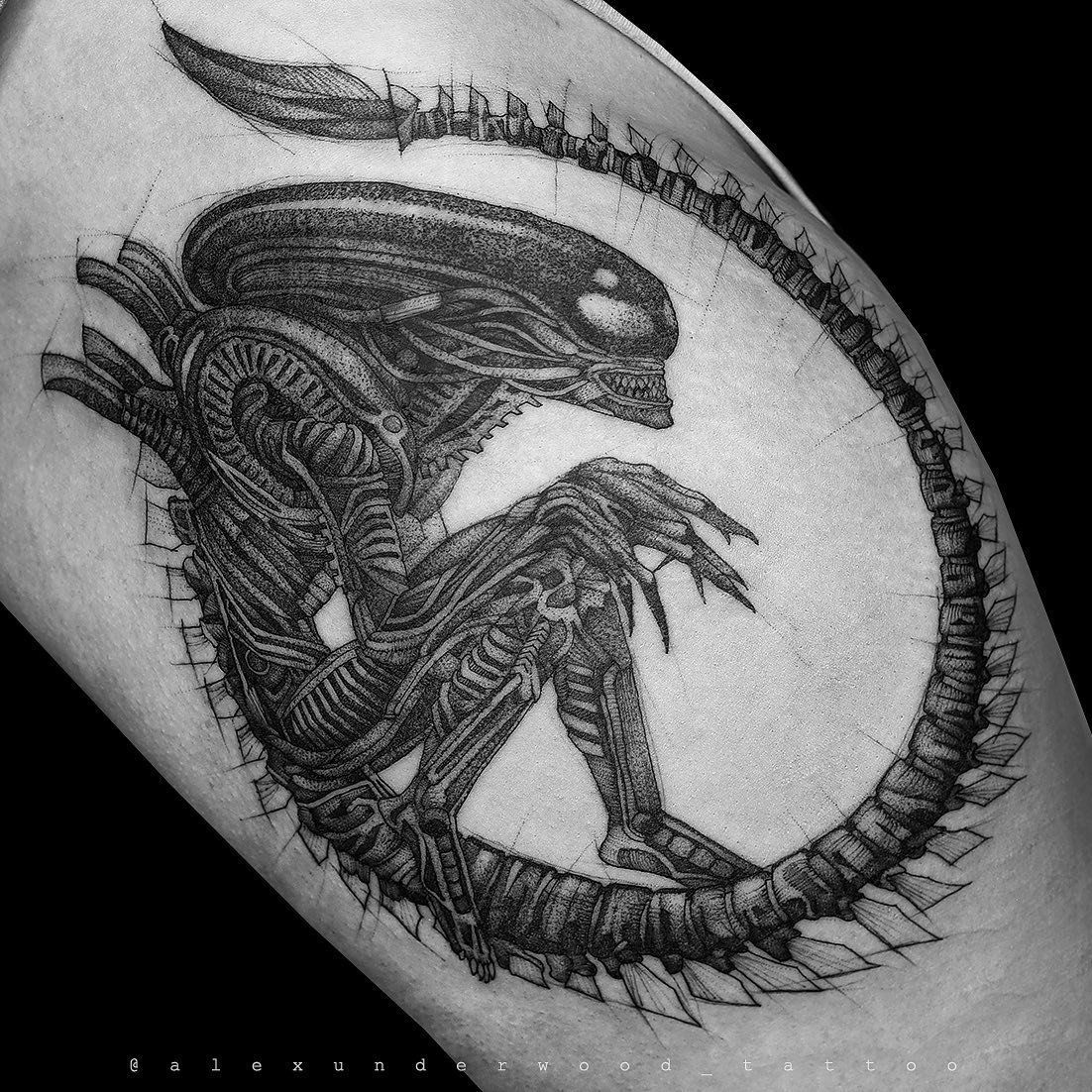 A black and white tattoo of an alien on a person 's leg