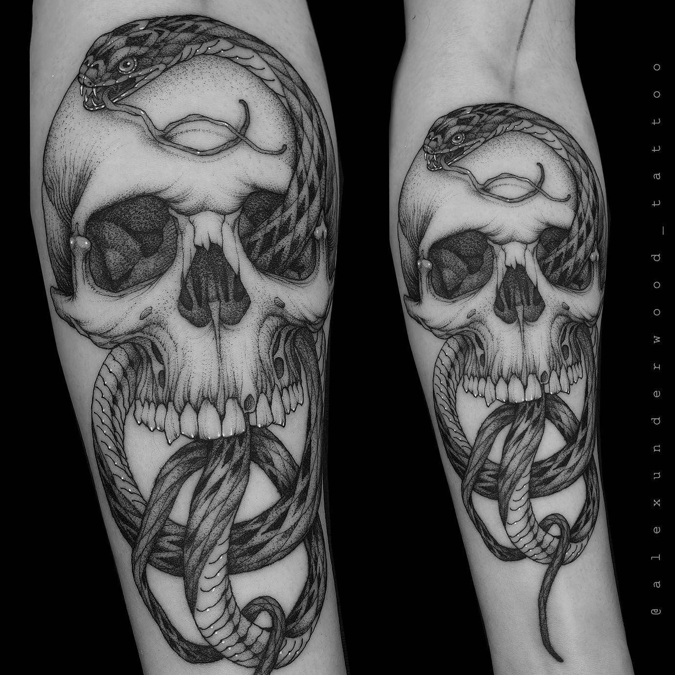A black and white tattoo of a skull with a snake around it