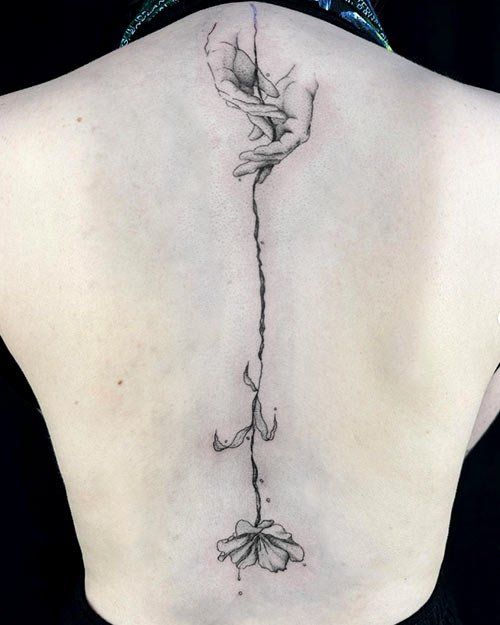A woman has a tattoo of a flower on her back