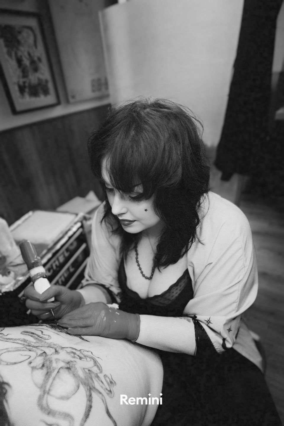 Person seated indoors, sketching at a table with art supplies, in black-and-white.
