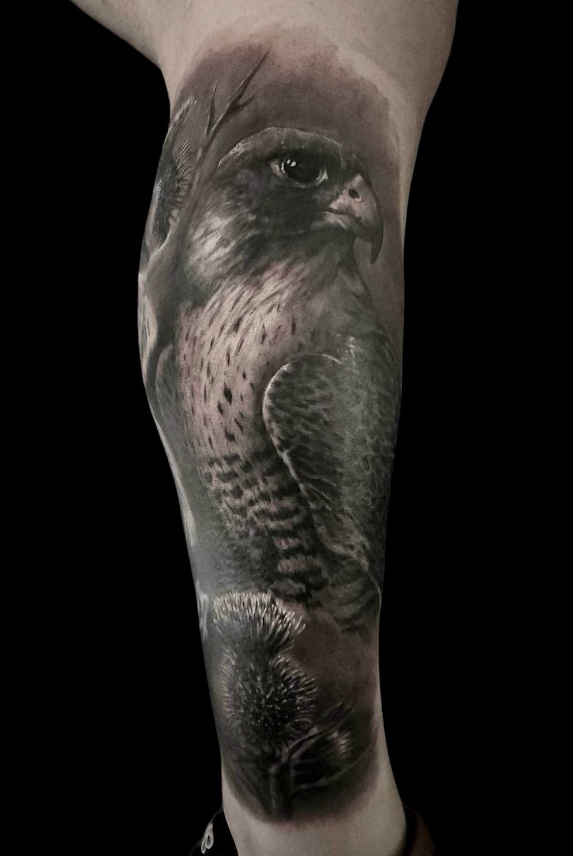 Black-and-gray tattoo of a woman's face on a forearm, shown against a black background