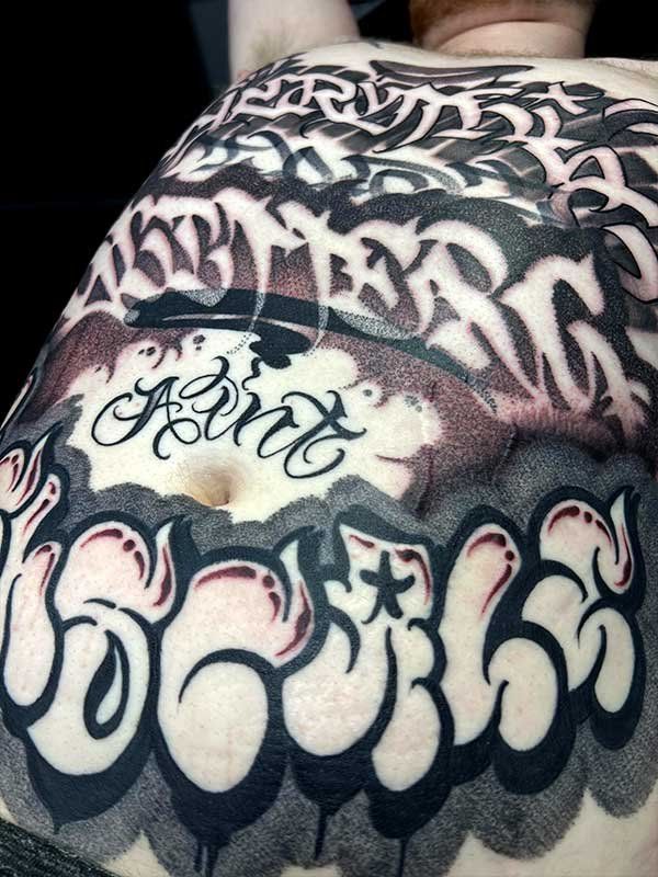 A close up of a person 's back with a graffiti tattoo on it.