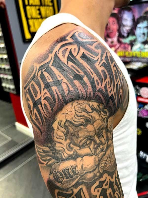 A man in a white tank top has a tattoo on his arm