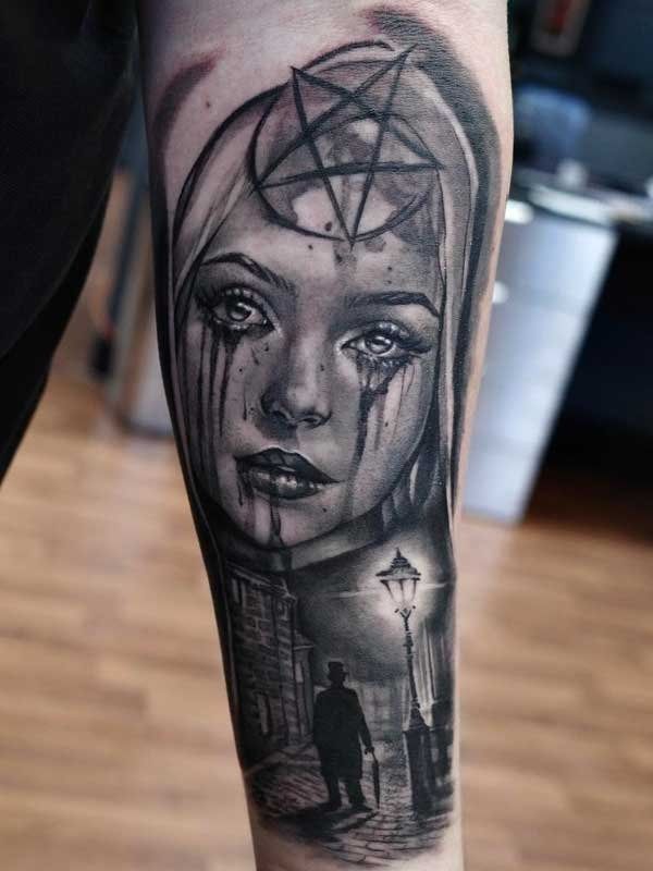 A black and white tattoo of a woman with a pentagram on her head.