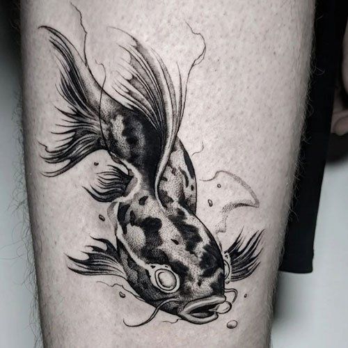 A black and white tattoo of a fish on a person 's leg.