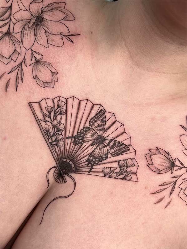 A woman has a tattoo of a fan and flowers on her chest.