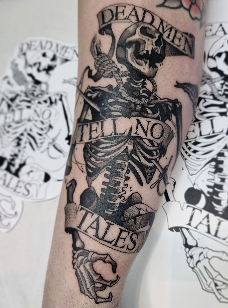 Black-and-gray tattoo of a skeleton with a banner reading “DEAD MEN TELLING TALES” on an arm.