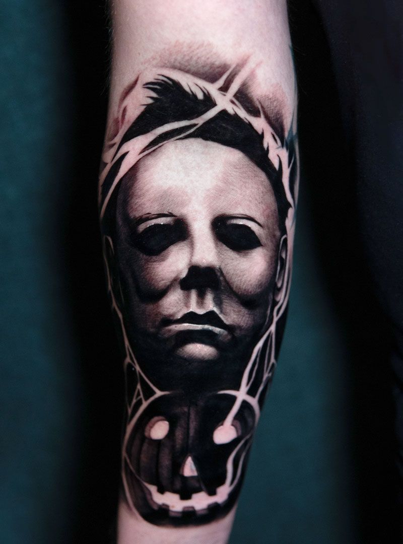 Black-and-gray tattoo of a Michael Myers-style mask over a skull on a forearm