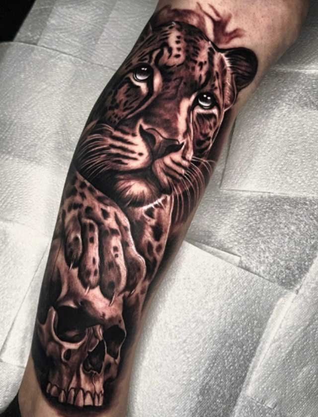 A tattoo of a tiger and a skull on a person 's leg.