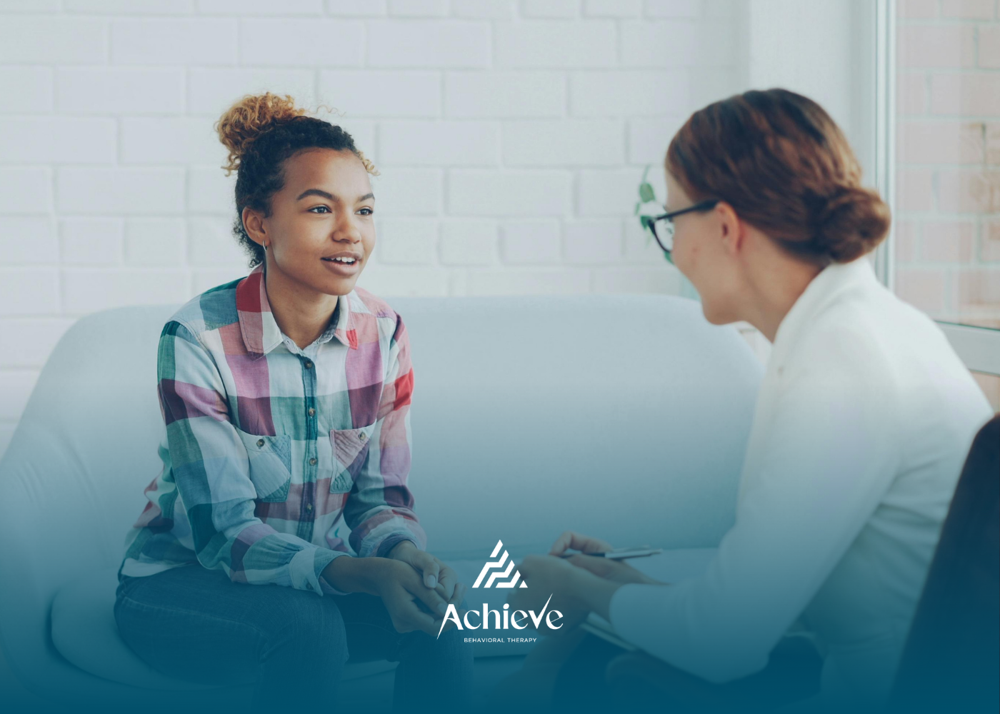 A consultant and her client talking across a table in a bright office.