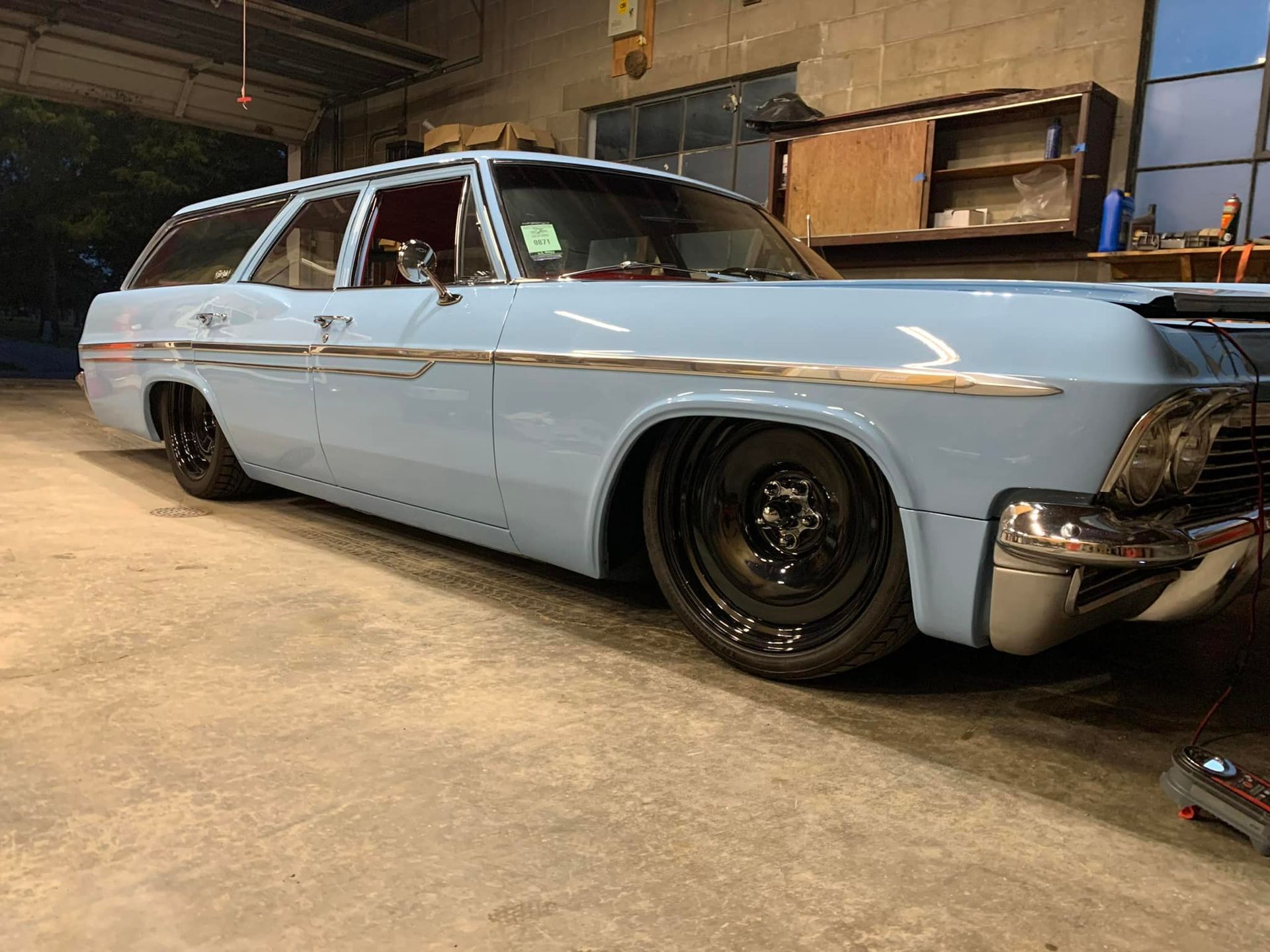 A blue station wagon is parked in a garage.