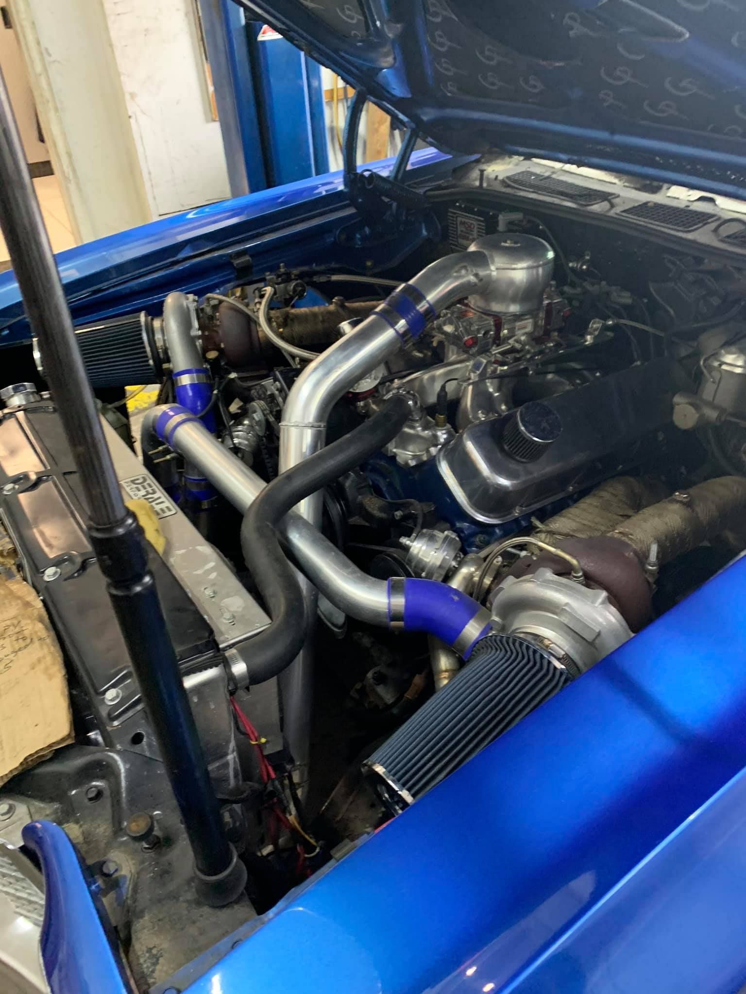 A close up of a blue car engine with the hood open.