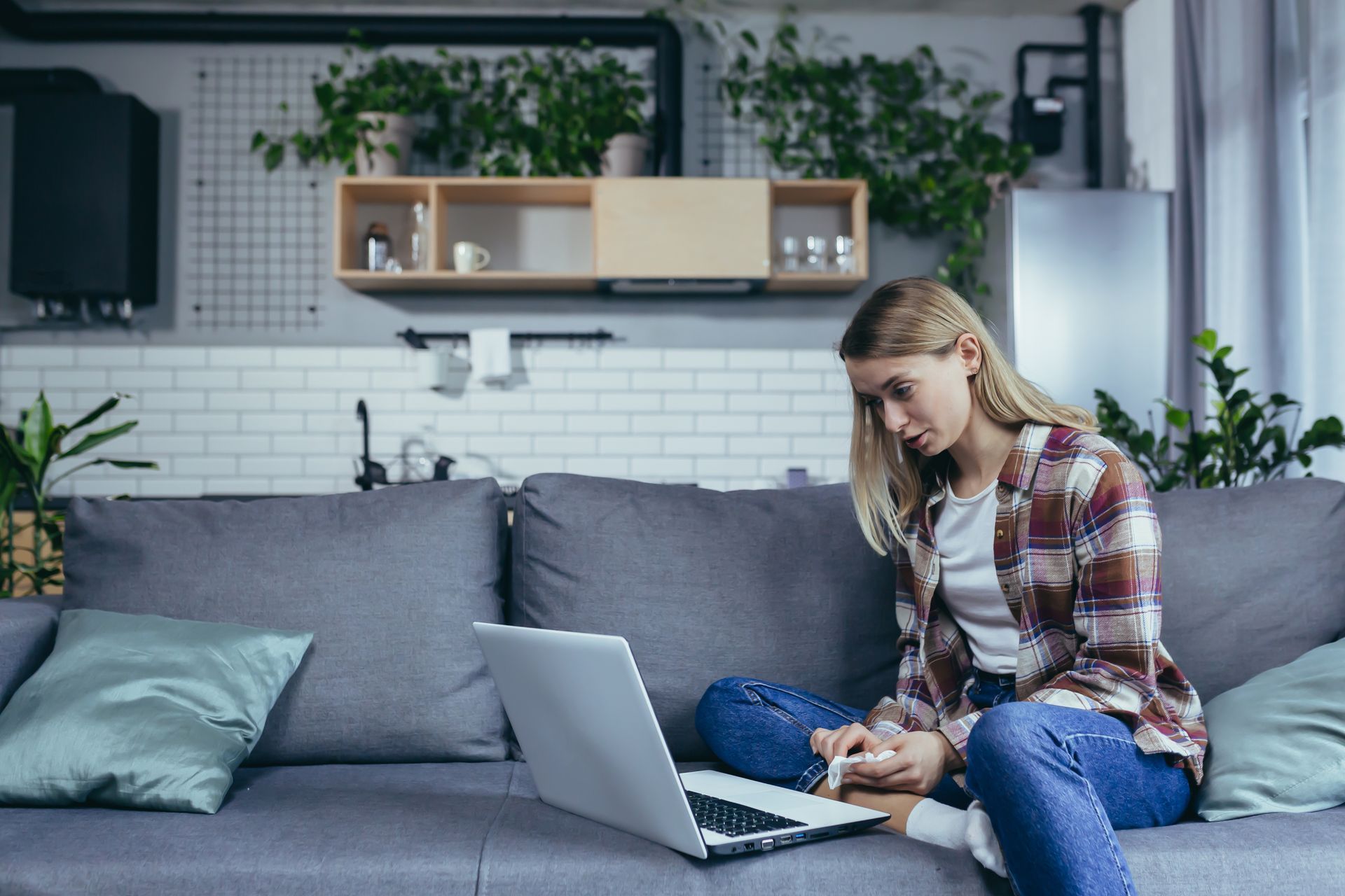A woman is sitting on a couch using a laptop computer.