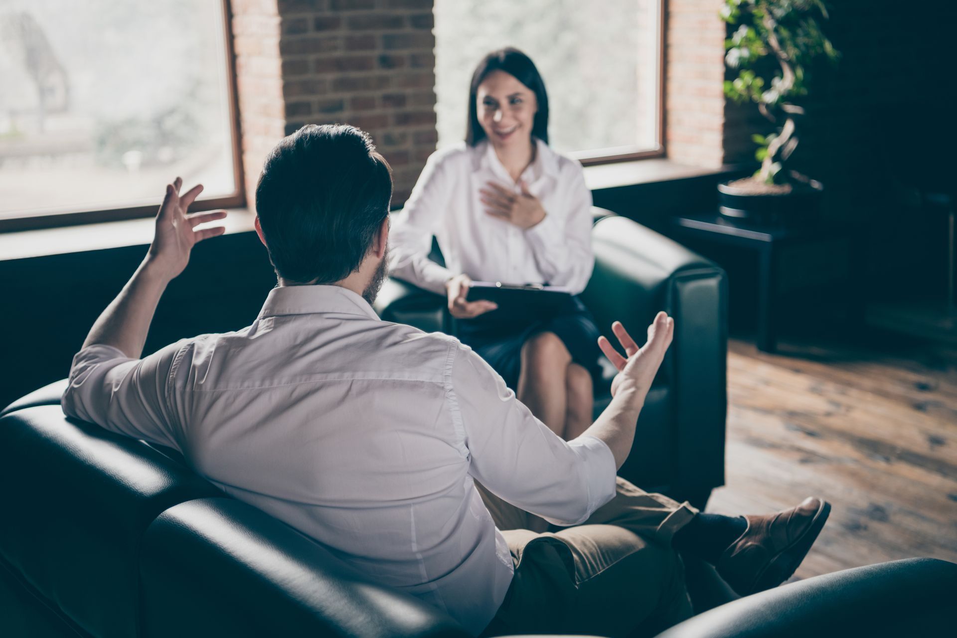 A man is sitting on a couch talking to a woman.