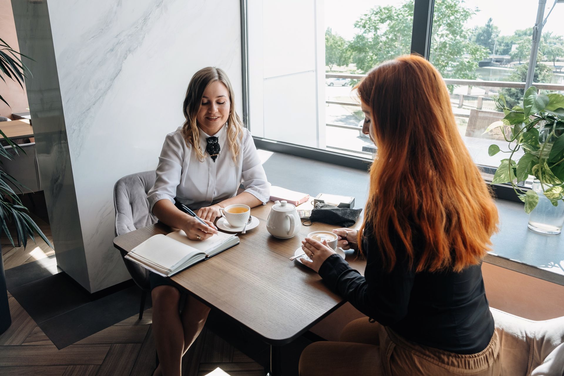 Two women are sitting at a table having a conversation.
