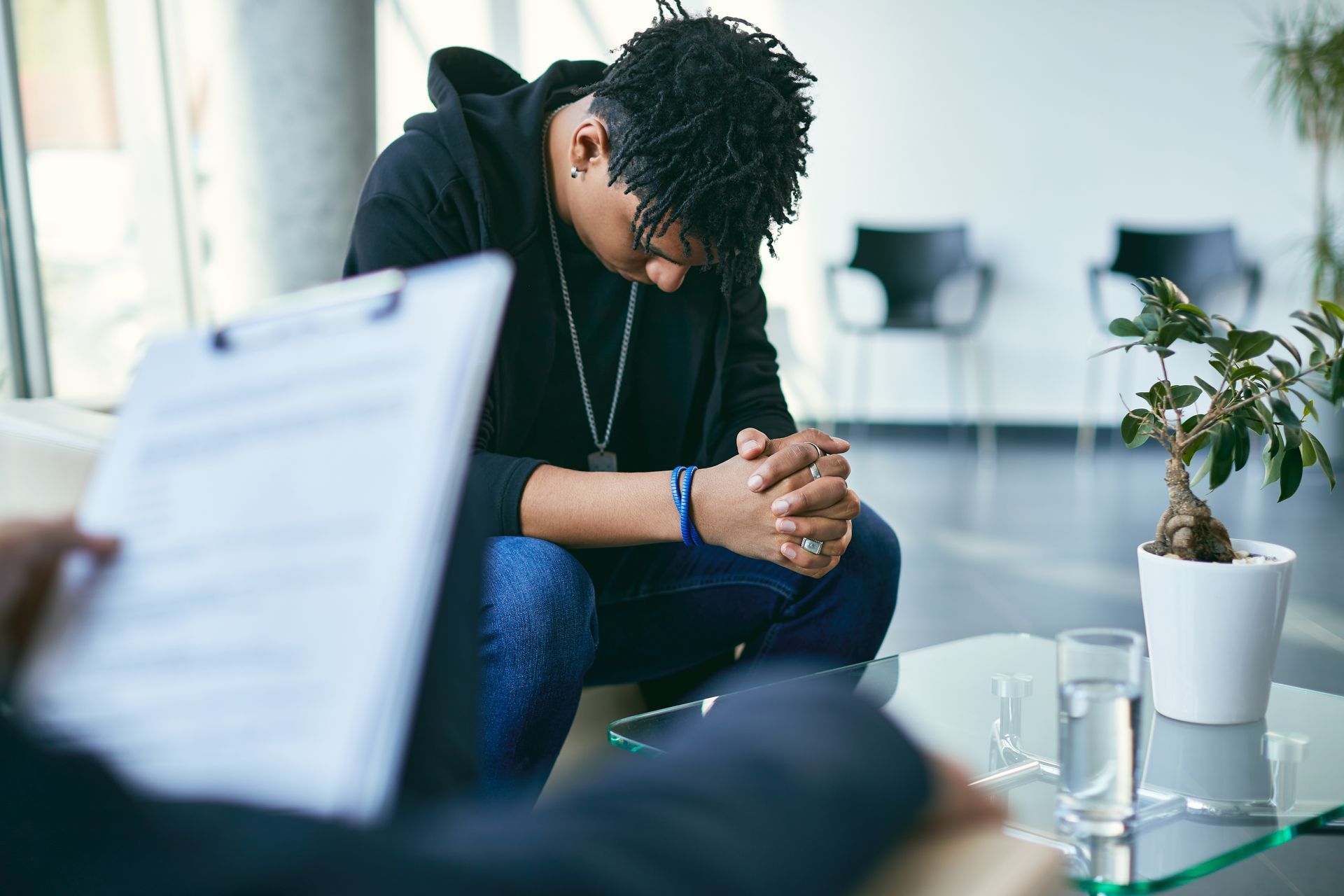 A young man is sitting at a table with his head down.
