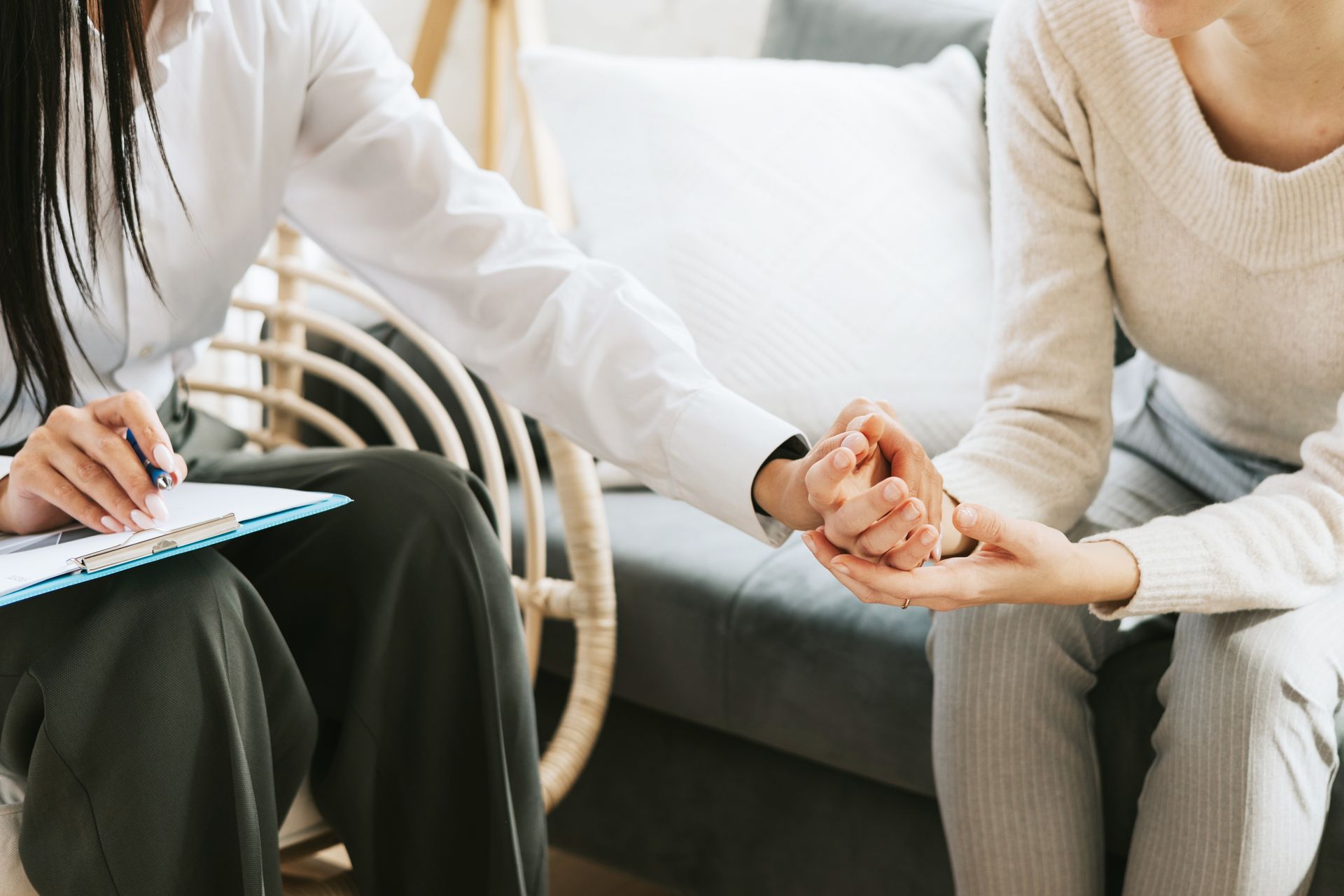 A woman is holding another woman 's hand while sitting on a couch.