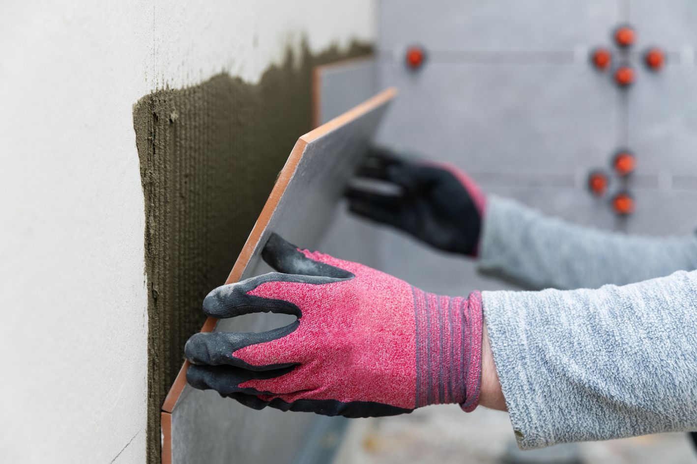 Bathroom fitter tiling a wall for a bathroom renovation project.