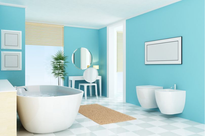 A large bathroom with a white bath, a white double sink vanities, white floor, and large windows overlooking a river.
