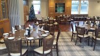 Dining room for golf club members to use at lunch. There are brown tables, white cloths, and brown and white chairs.