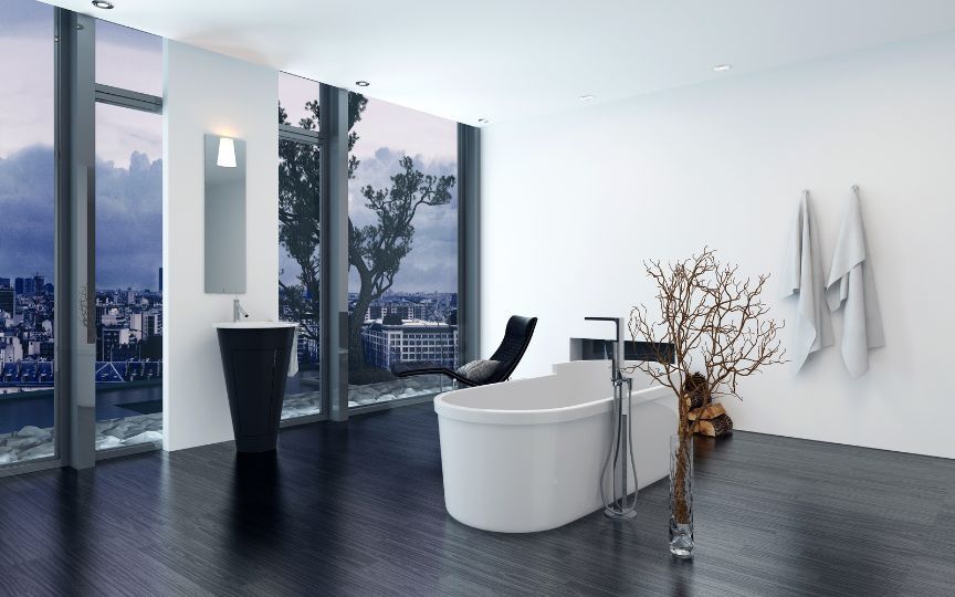 Free-standing bathtub in a bathroom overlooking a large city at nighttime.