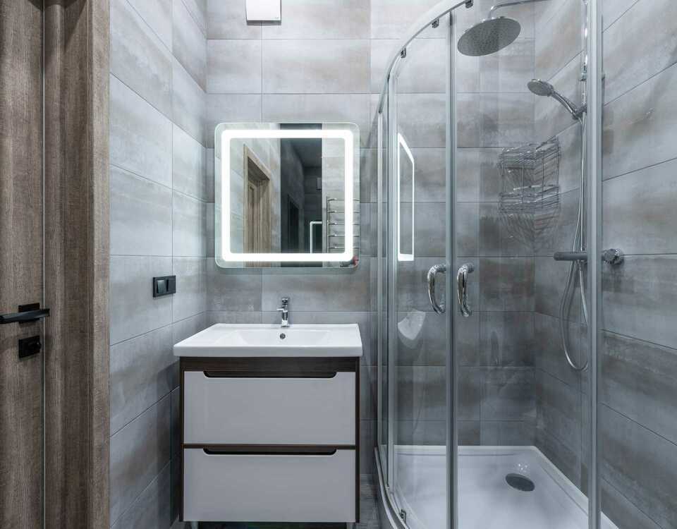 Modern bathroom with a grey theme including a sliding shower, one sink and two drawers.