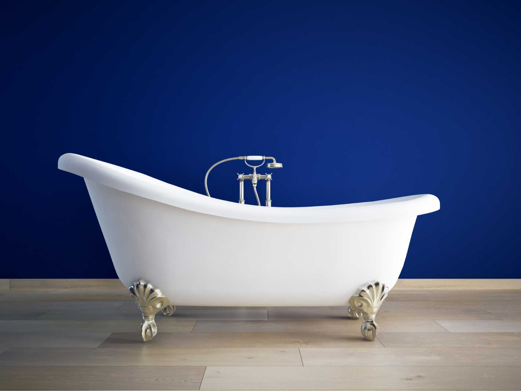 Slipper bath with a blue wall in the background and oak floor.