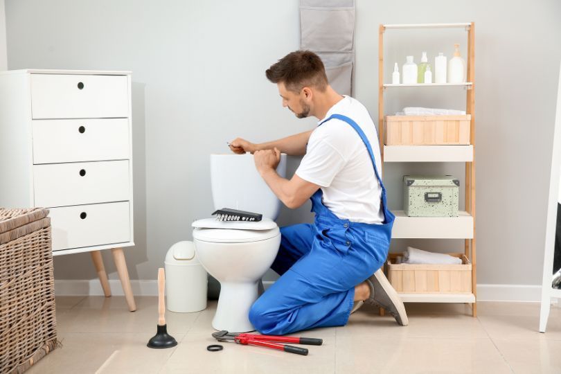 A bathroom installer, fitting a toilet in a new bathroom.
