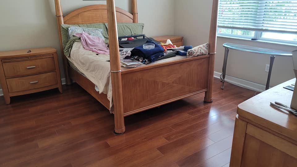 Bedroom with wooden furniture and hardwood floor.  Four-poster bed is center.  Nightstand left.  Window right.