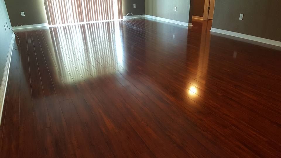 Polished, dark wood floor in a sunlit room, reflecting light from a window.