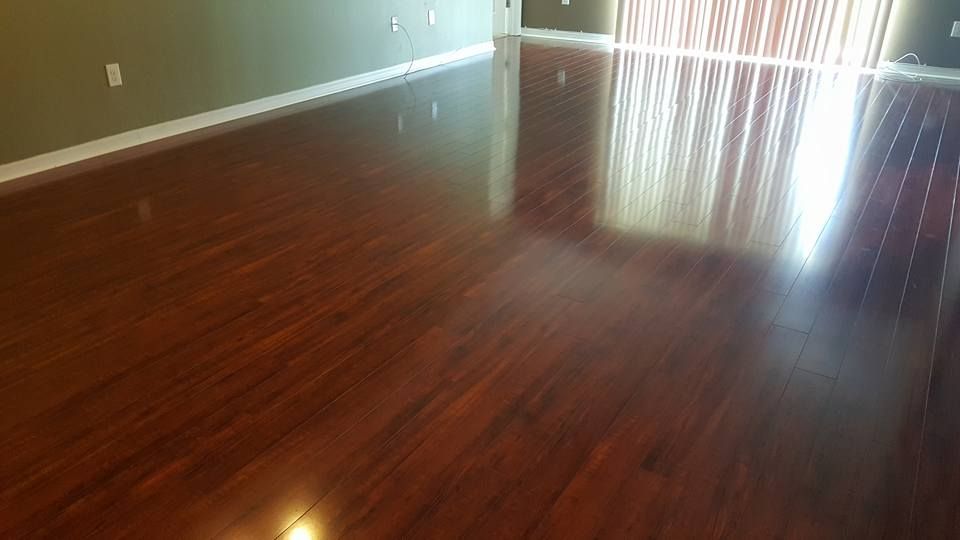 Glossy reddish-brown hardwood floor reflecting light from a sliding glass door.