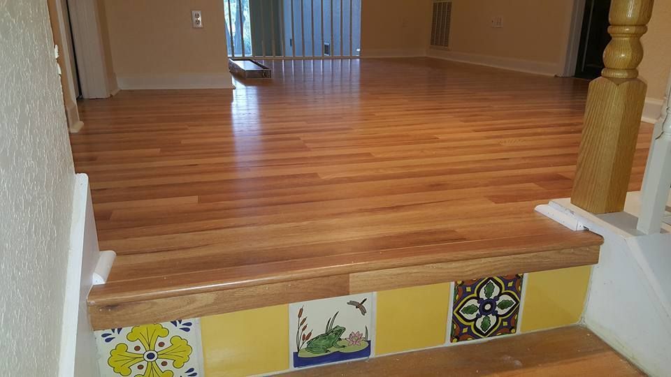 Wooden steps with decorative yellow tiles leading to a room with hardwood floors.