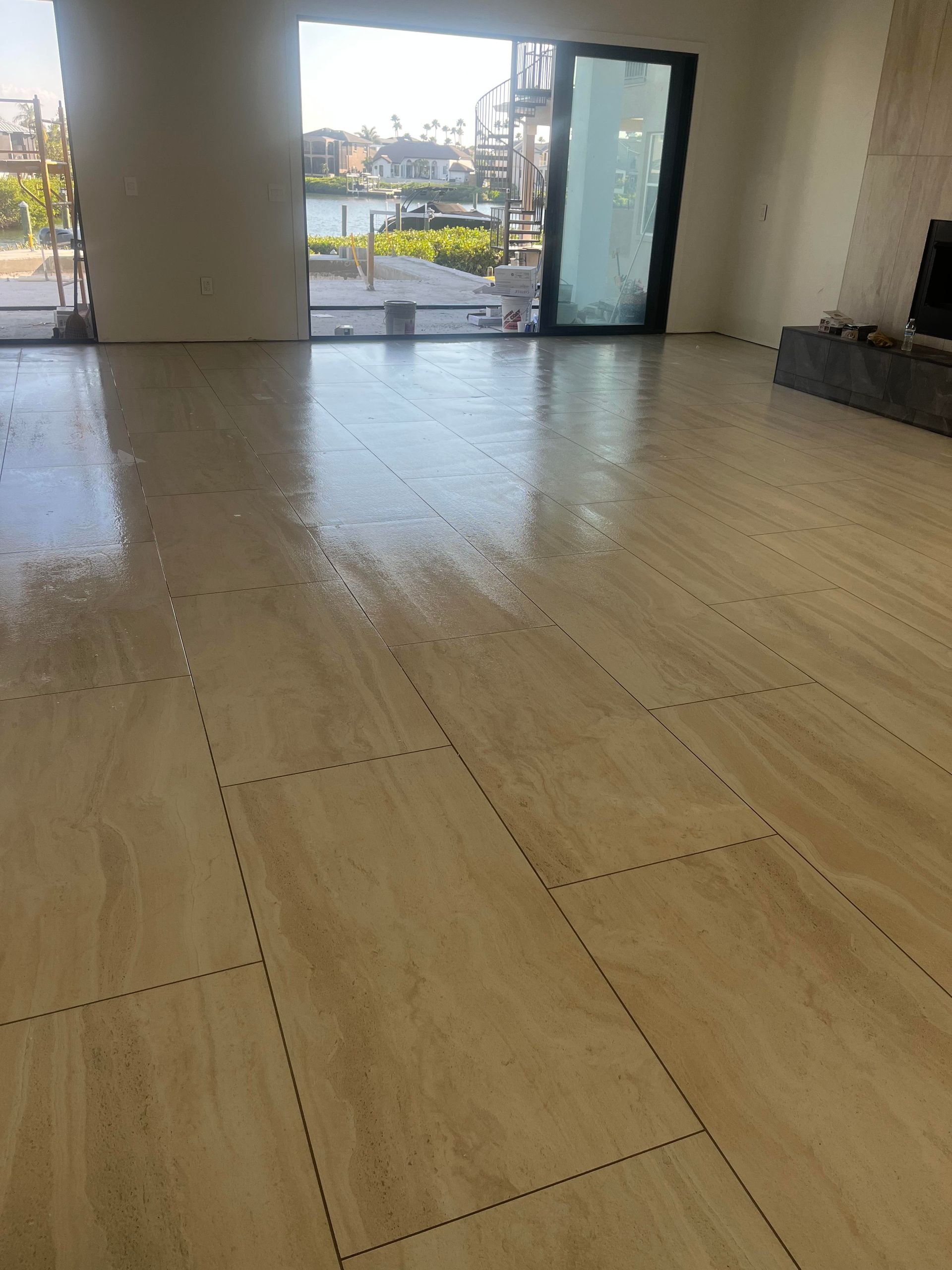 Empty indoor room with light wood floor and large open glass doors to a patio and street view