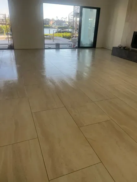 Refinished hardwood floor in a room with light blue walls and a window covered in plastic sheeting.