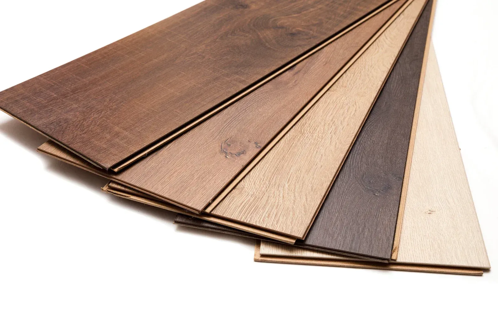 Assorted wood flooring samples in various shades, stacked, angled, on a white background.