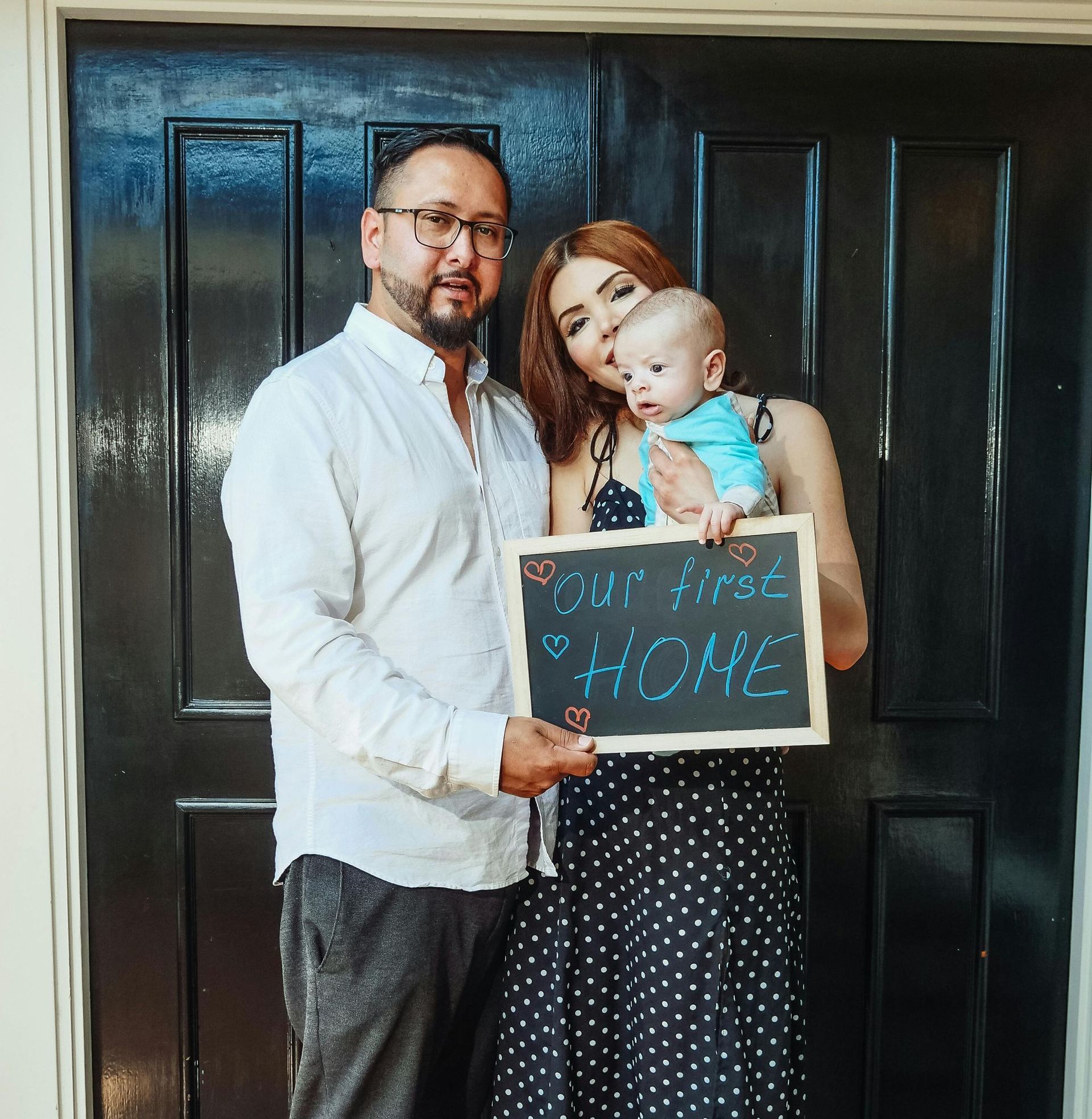 A man and woman holding a baby and a sign that says