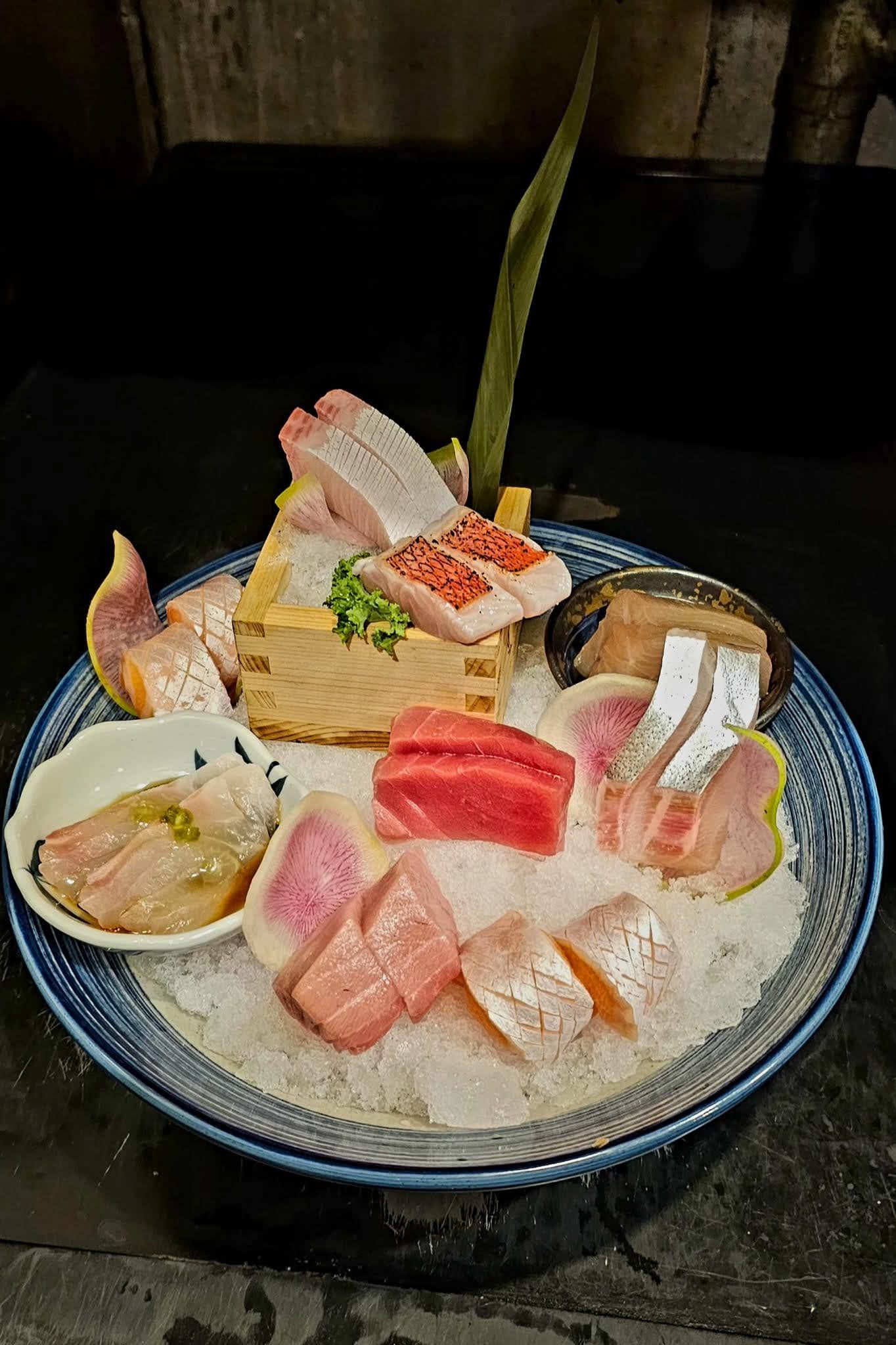 Bowl of assorted colorful sashimi and sushi with rice on a table