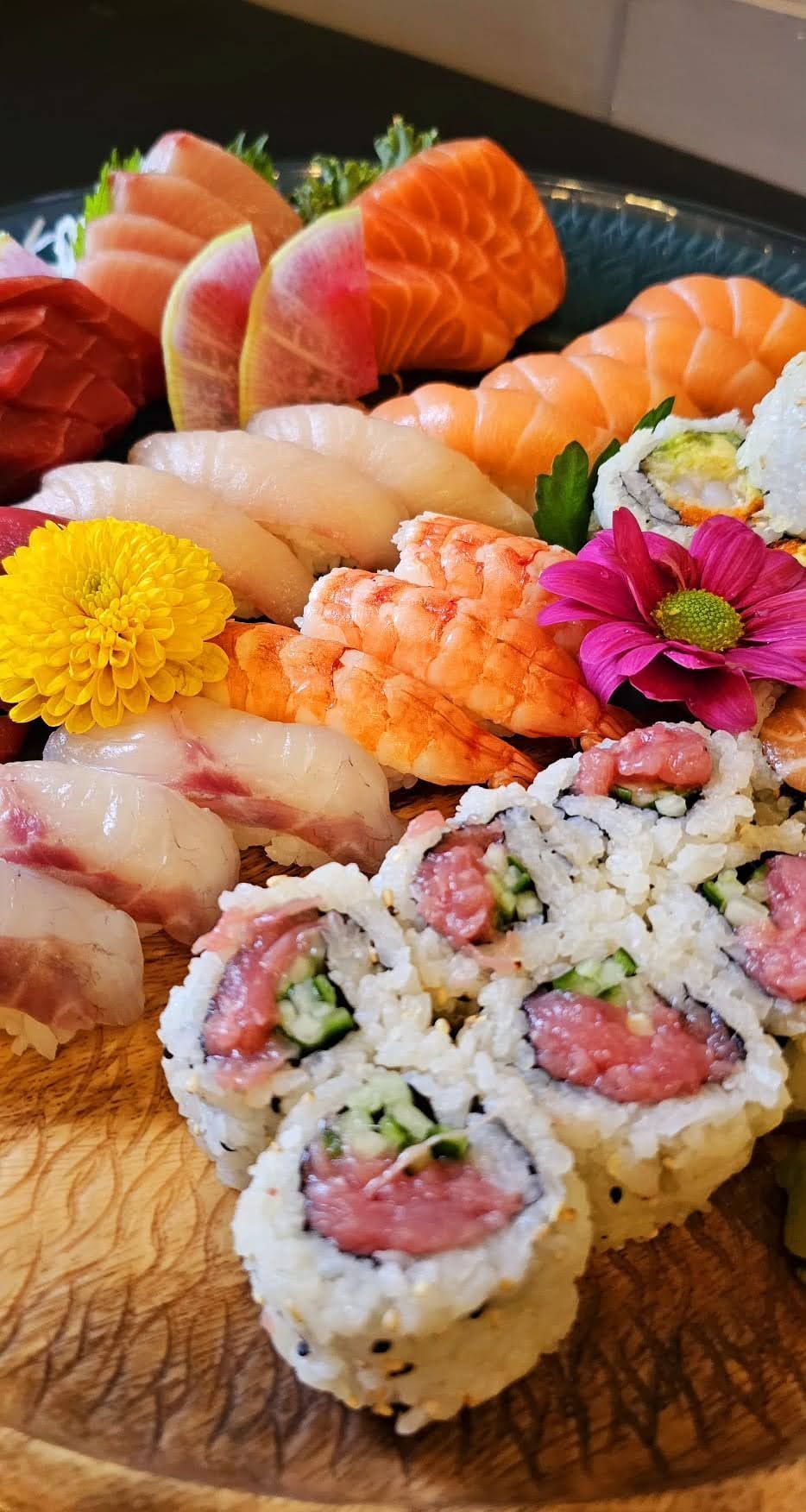 Assorted sushi platter with salmon nigiri, shrimp, rolls, and garnishes on a wooden board